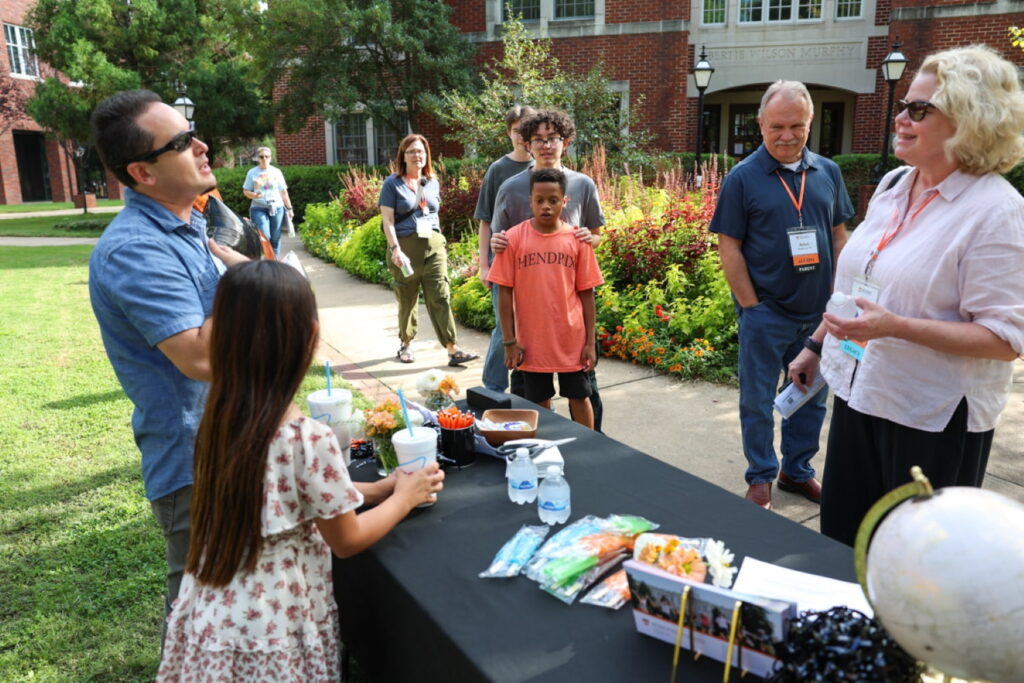 Nine people stand in line outside at a tabling event for the Hendrix Murphy Foundation.