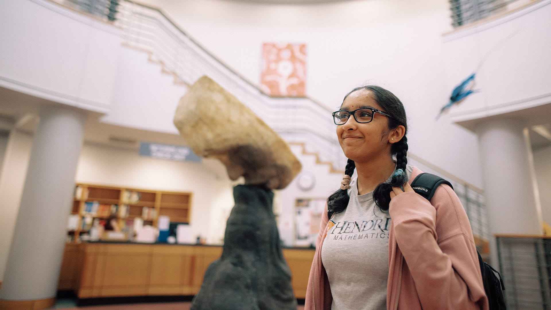 One smiling Hendrix student stands in a well-lit indoor room next to a statue of art.