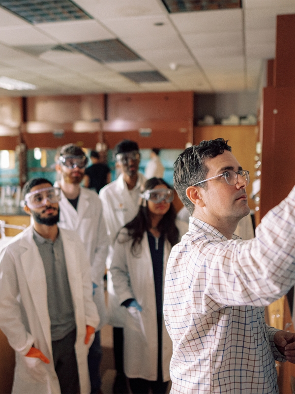 Faculty member works with students in a laboratory classroom.