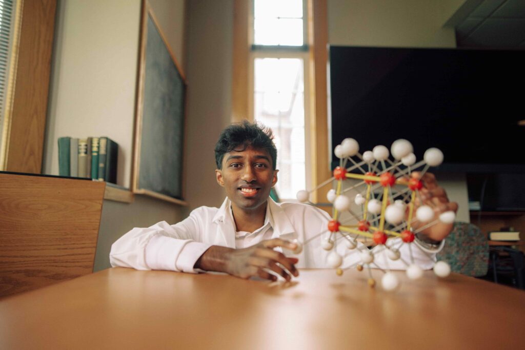 A student displaying a model of a molecule in a science classroom.