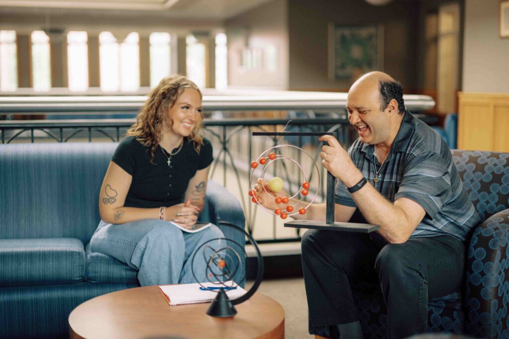 A professor and a student working with rotating models of atoms.