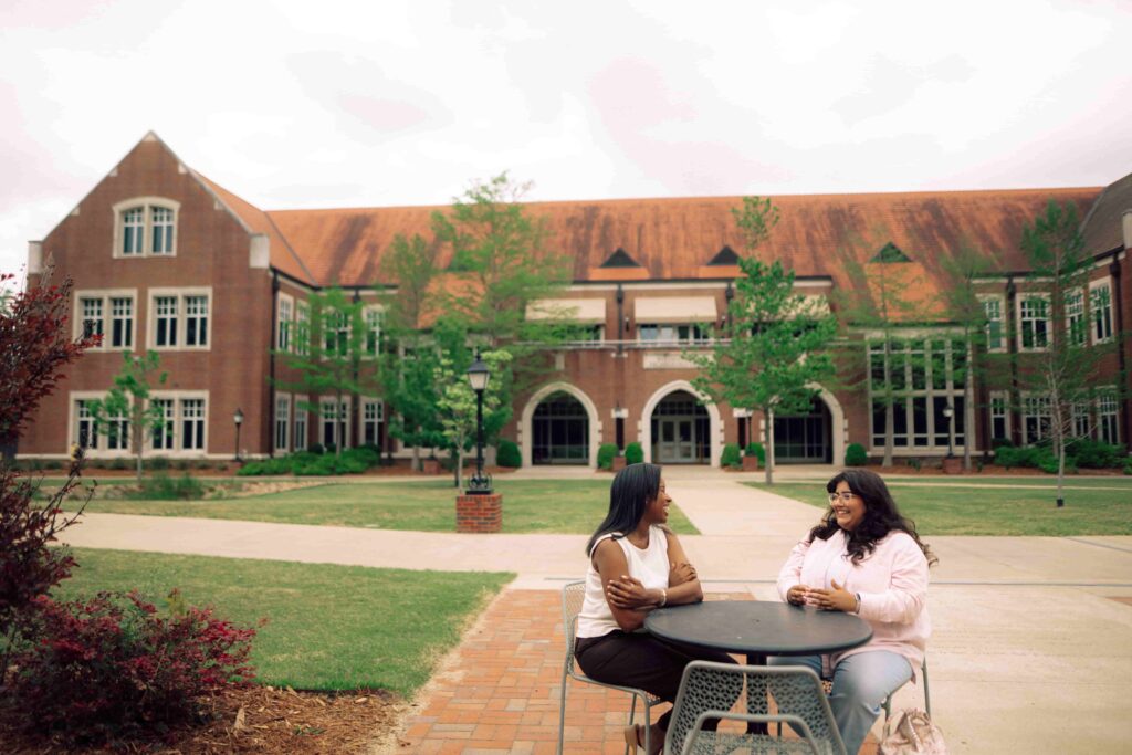 Two women sitting at an outdoor table on the Hendrix campus.