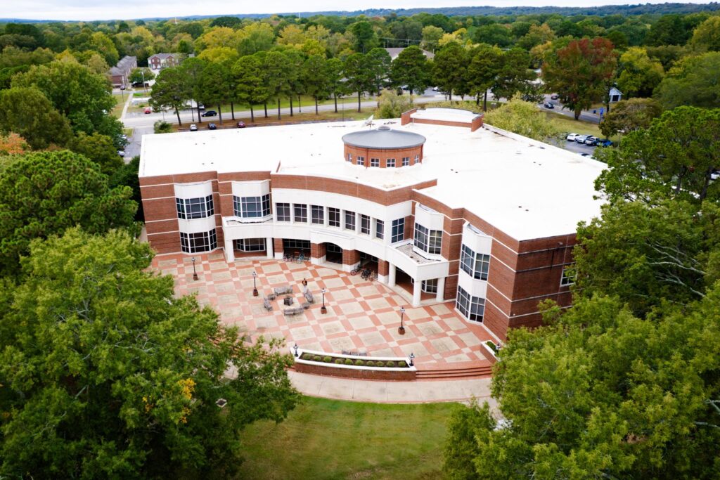 Aerial view of Bailey Library, brick and stone building surrounded by large green trees.