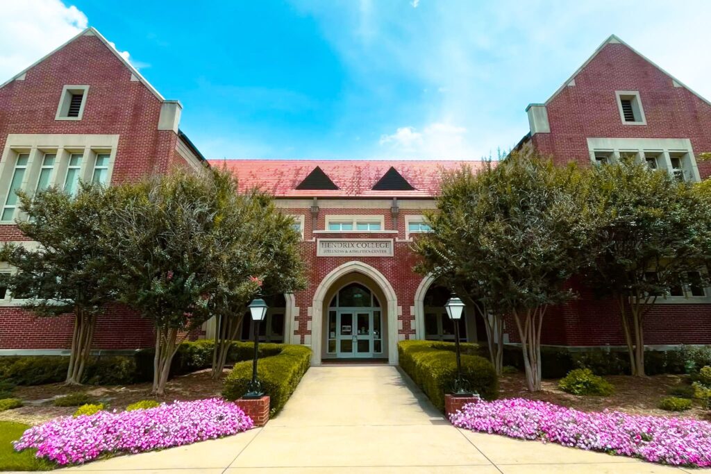 Brick and stone exterior of a building on the Hendrix campus, with colorful flowers lining the path to the entrance.