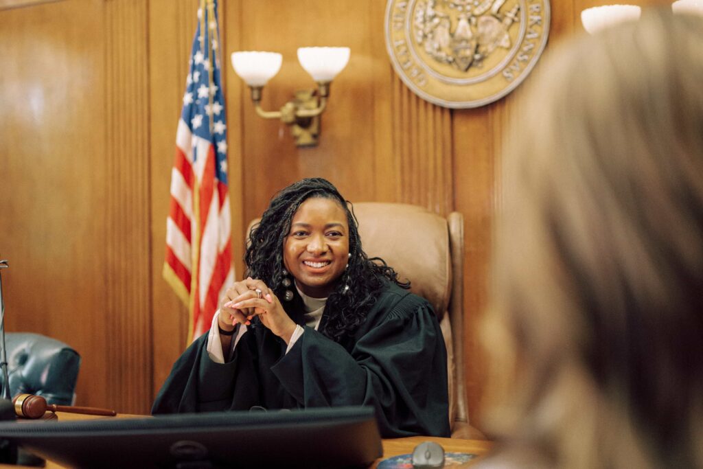 A judge in black robes sitting behind the bench in a courtroom.