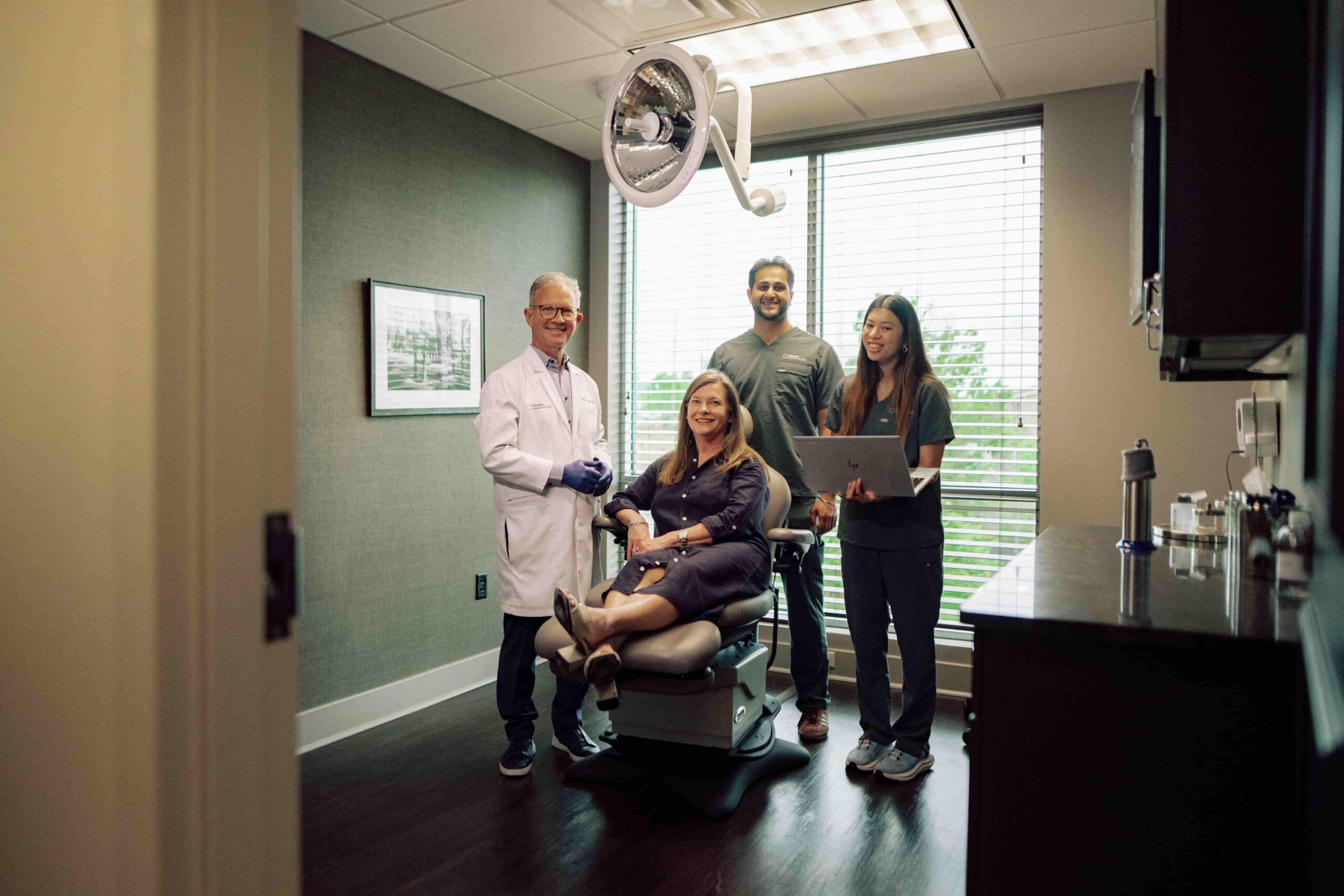 Two students and a doctor in an exam room with a patient.