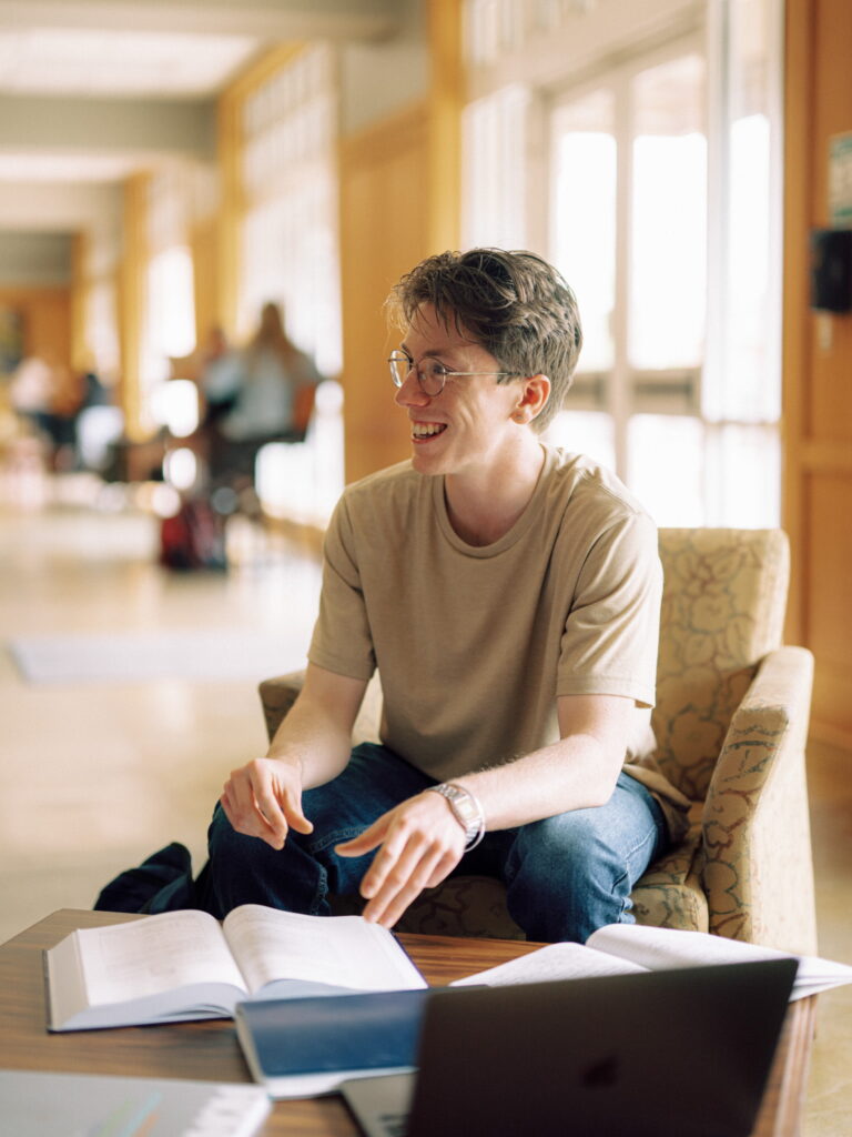 A smiling Hendrix student studying at a table in the lobby of a building.