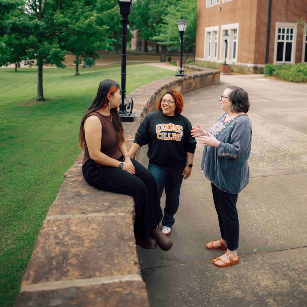 An advisor talking to two students outside on the Hendrix campus.