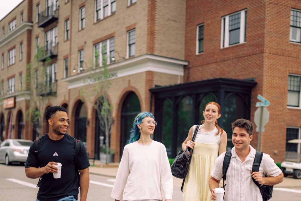 A group of Hendrix students walking across the street near apartment buildings.