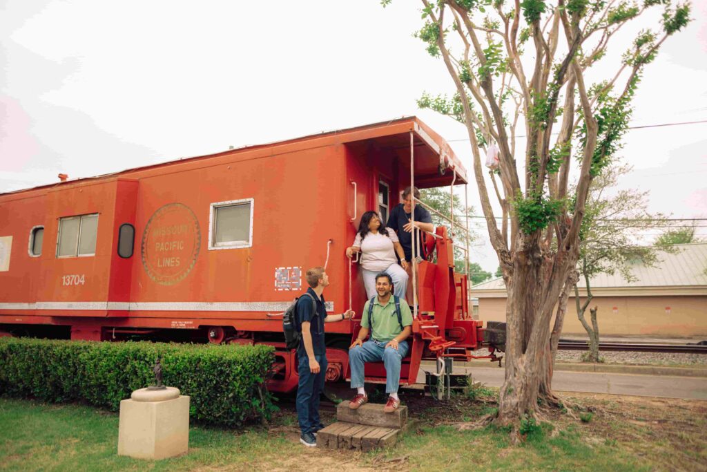 Four students standing on the back of a stationary railcar.