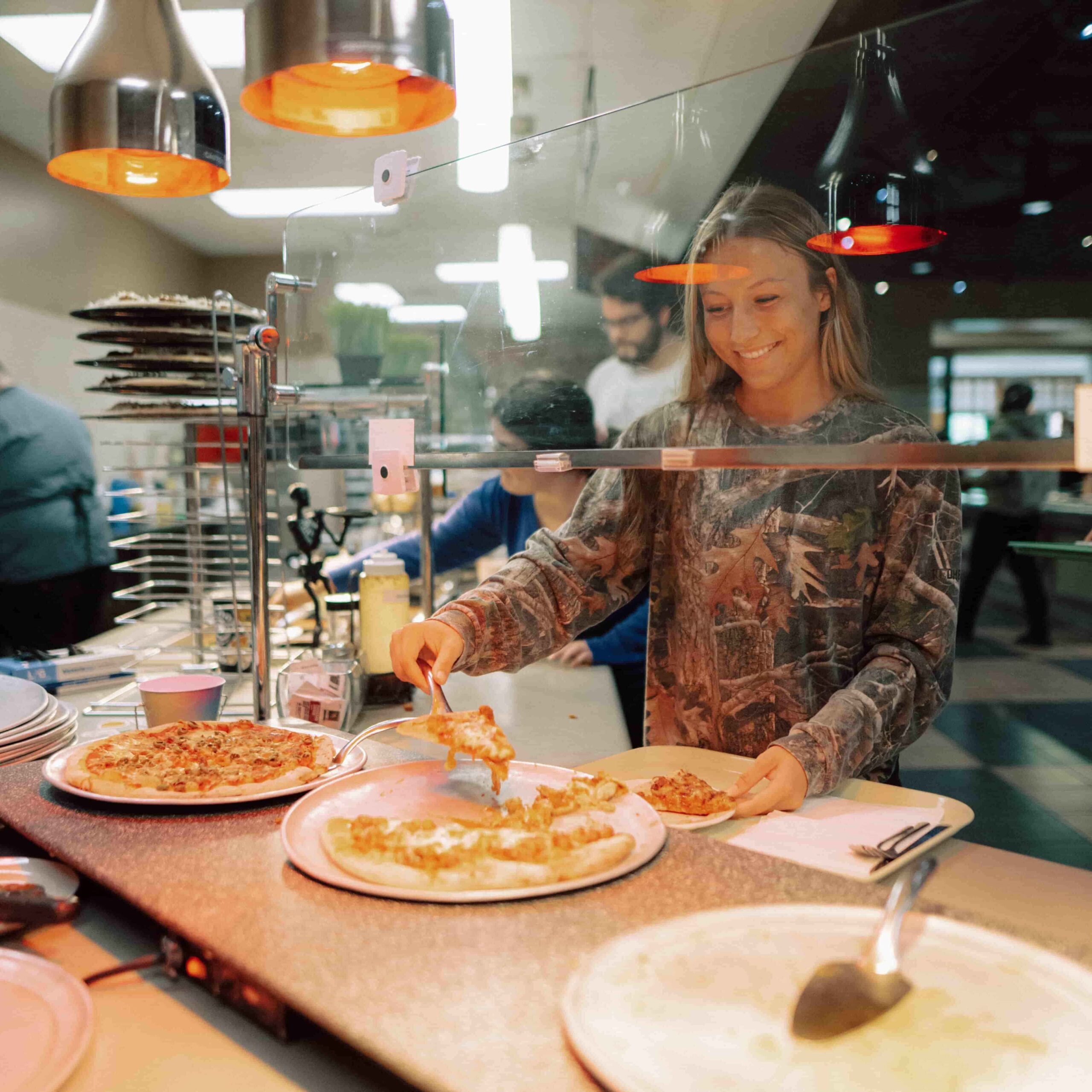 A student getting a piece of pizza at an on campus dining facility.
