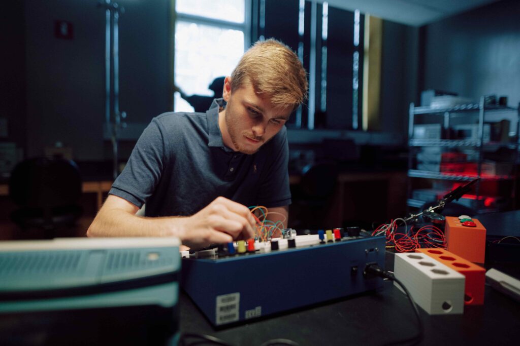 A student working with the wiring on an electronics board.