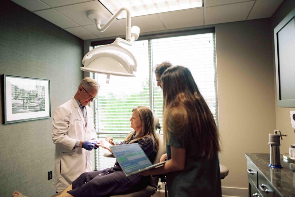 A doctor examining a patient's hand while two students observe.