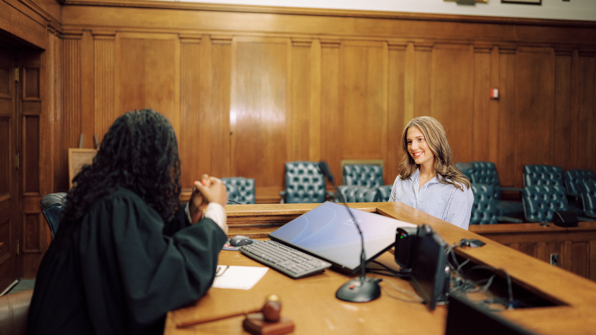 A smiling Hendrix College student speaks from the witness stand to a judge in a wood-paneled courtroom setting.
