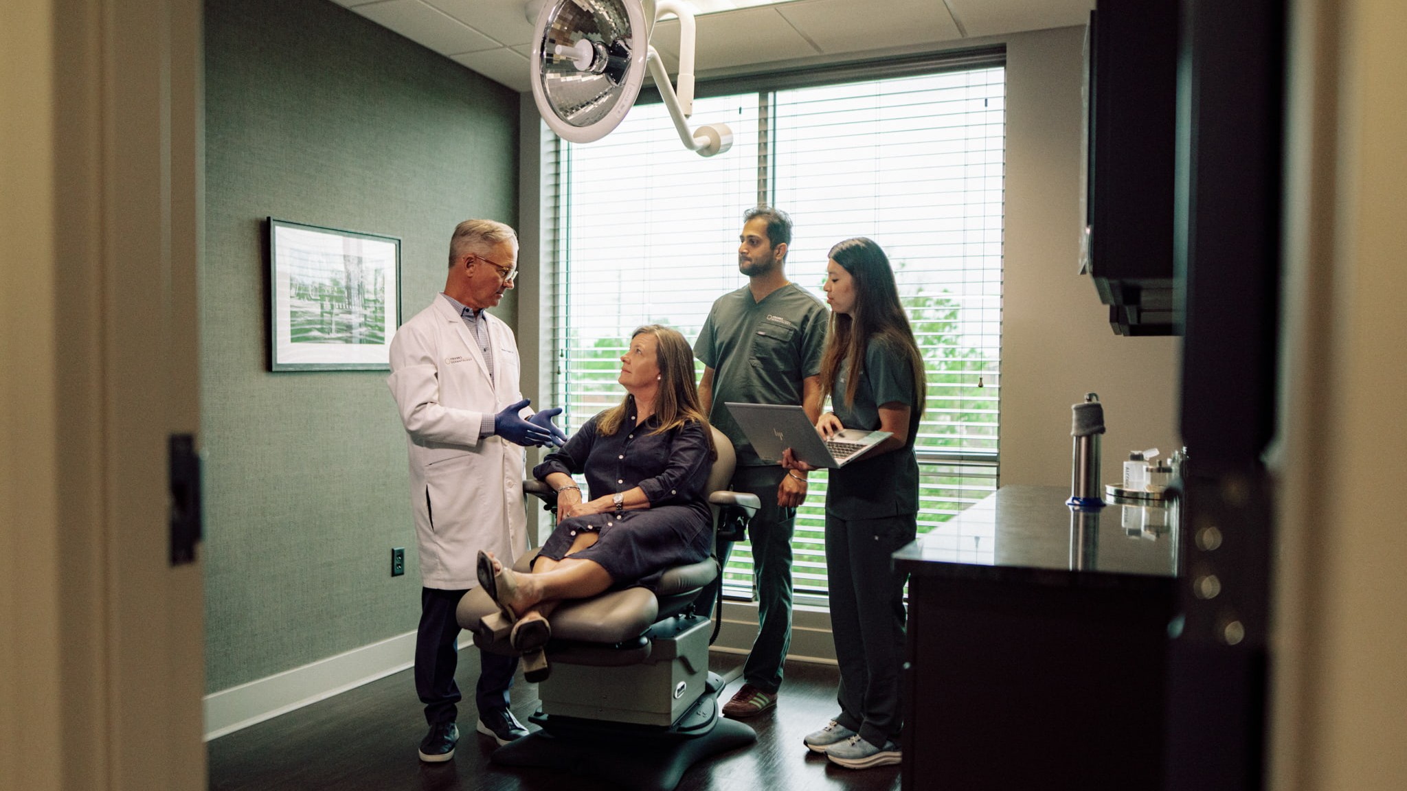 A medical professional talks to a patient while two Hendrix College students in scrubs observe during their clinical co-op.