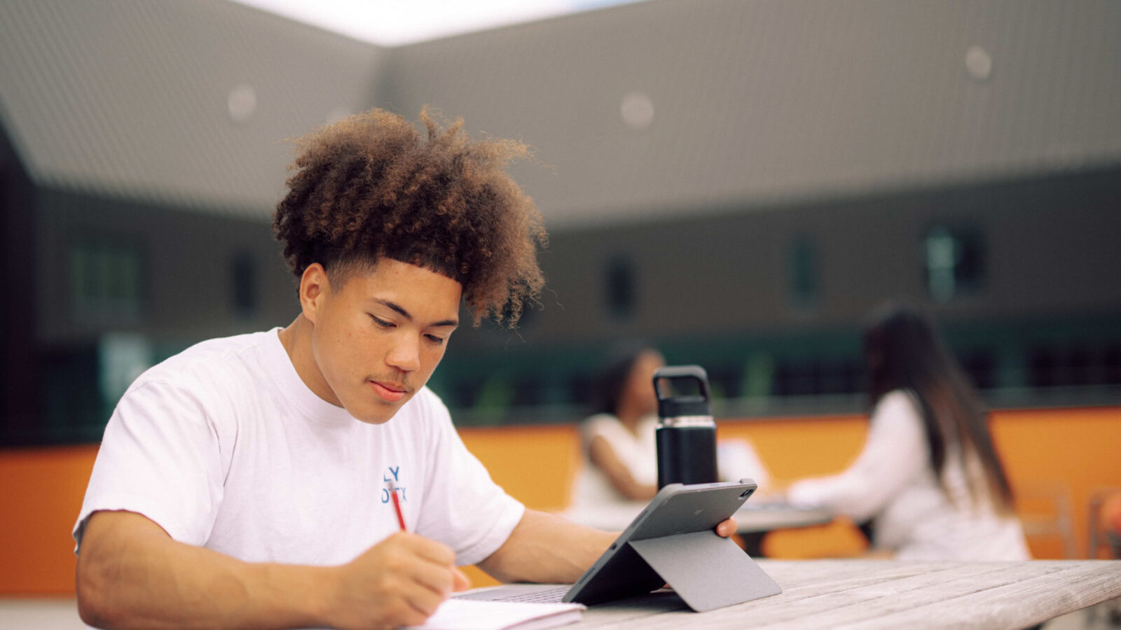 Accounting major student studying with a tablet and notebook while seated at an outdoor table on the Hendrix campus.