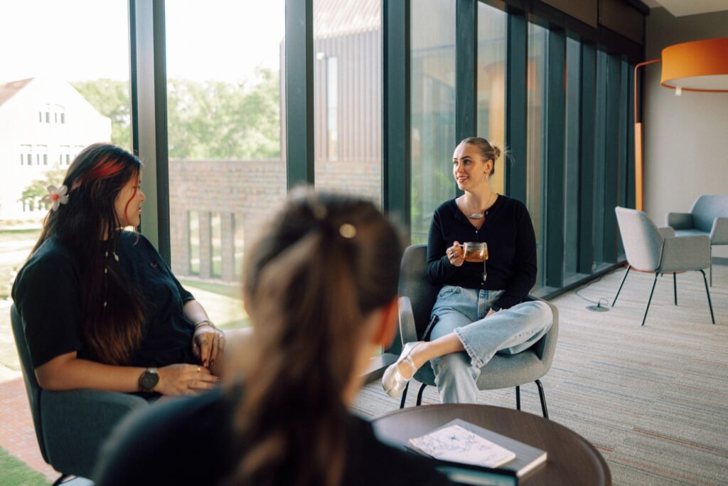 A career counselor speaking to two students around a table in a lounge area.