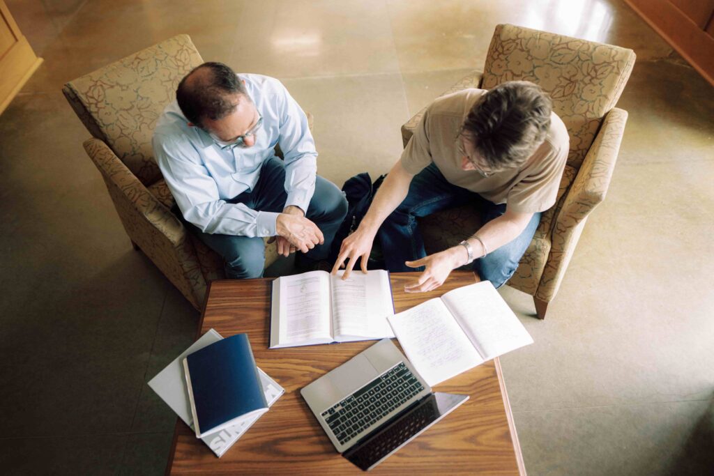 An advisor and a student reviewing information in a text book.