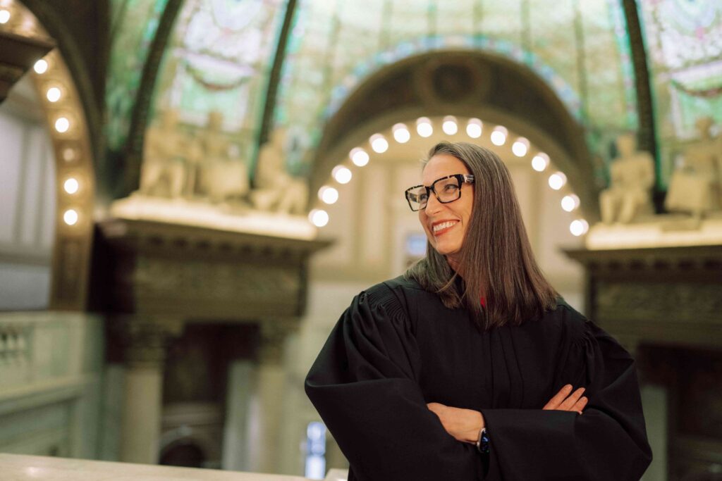 A woman wearing a black robe standing in the rotunda of a building.