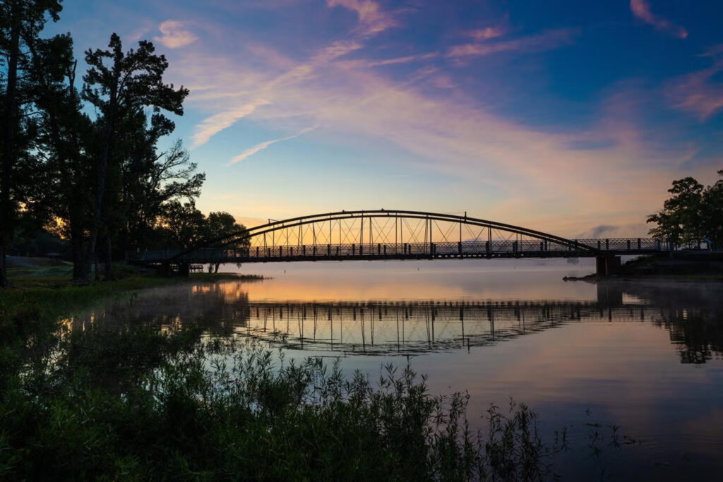 Sunset over Beaverfork Lake, with a bridge spanning the lake in the background.