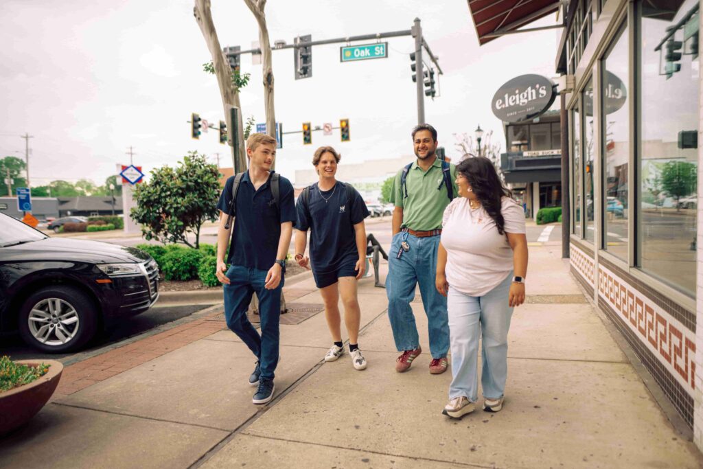 A group of four students walking down the sidewalk in Conway, Arkansas.