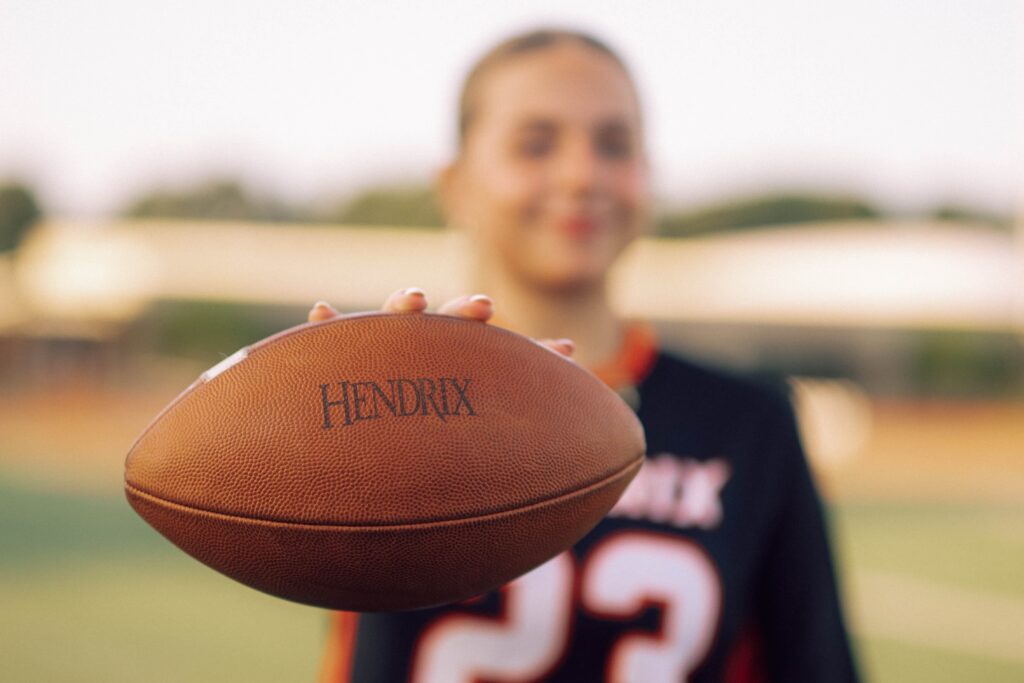 A student holding a football that has the Hendrix name printed on it.