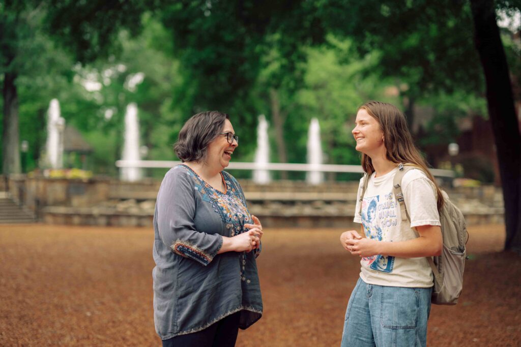 A faculty member and a student having a conversation on campus.