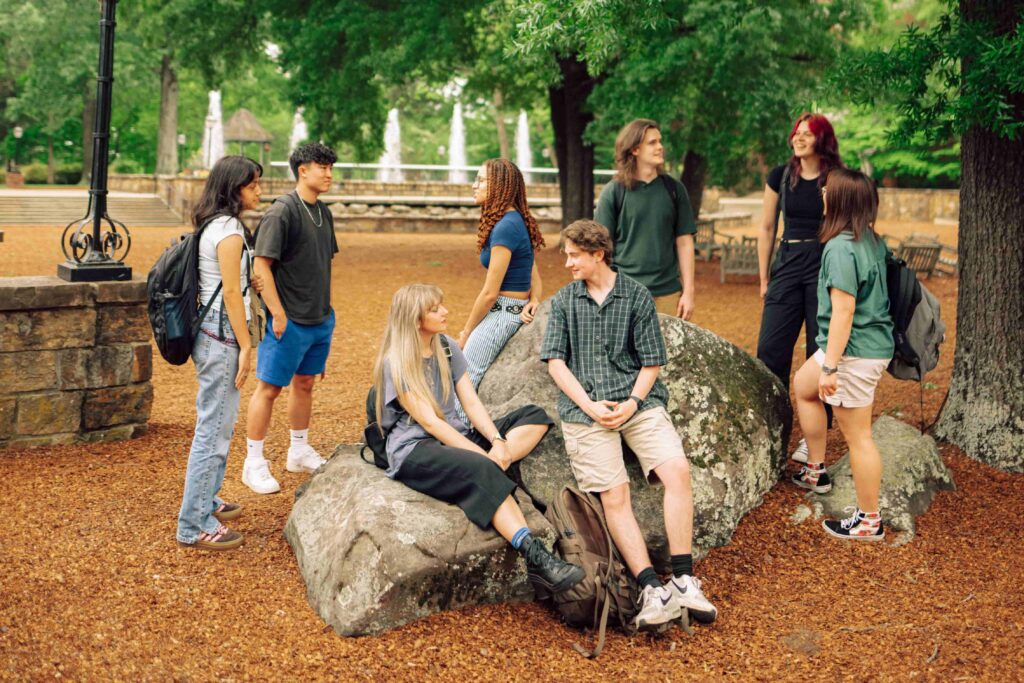 A group of eight students gathered around a rock outcropping on campus.