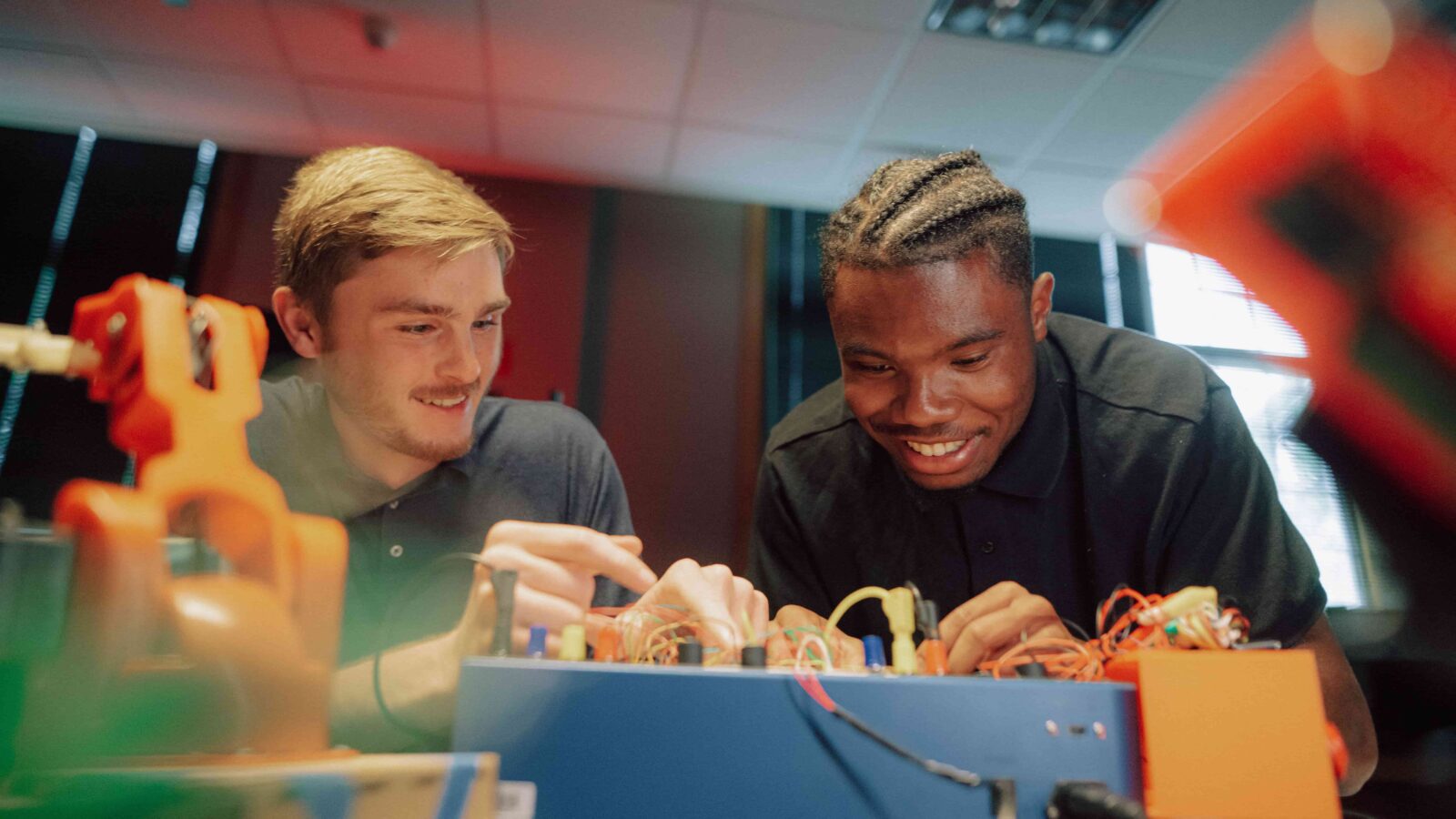 Two students working with wires on an electronics board.