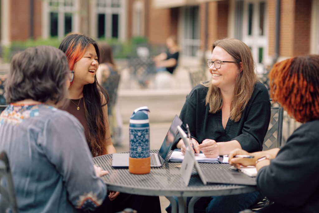 Two Hendrix faculty and two Hendrix students sitting at an outdoor table together.