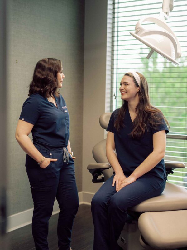Two students in medical scrubs having a conversation in a patient exam room.