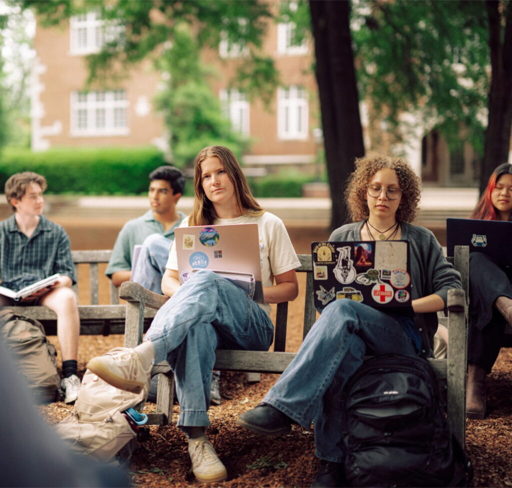 A group of Hendrix College students listening in an outdoor classroom.