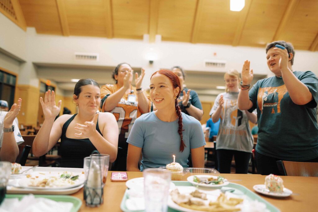 A group of people singing to a student on their birthday.