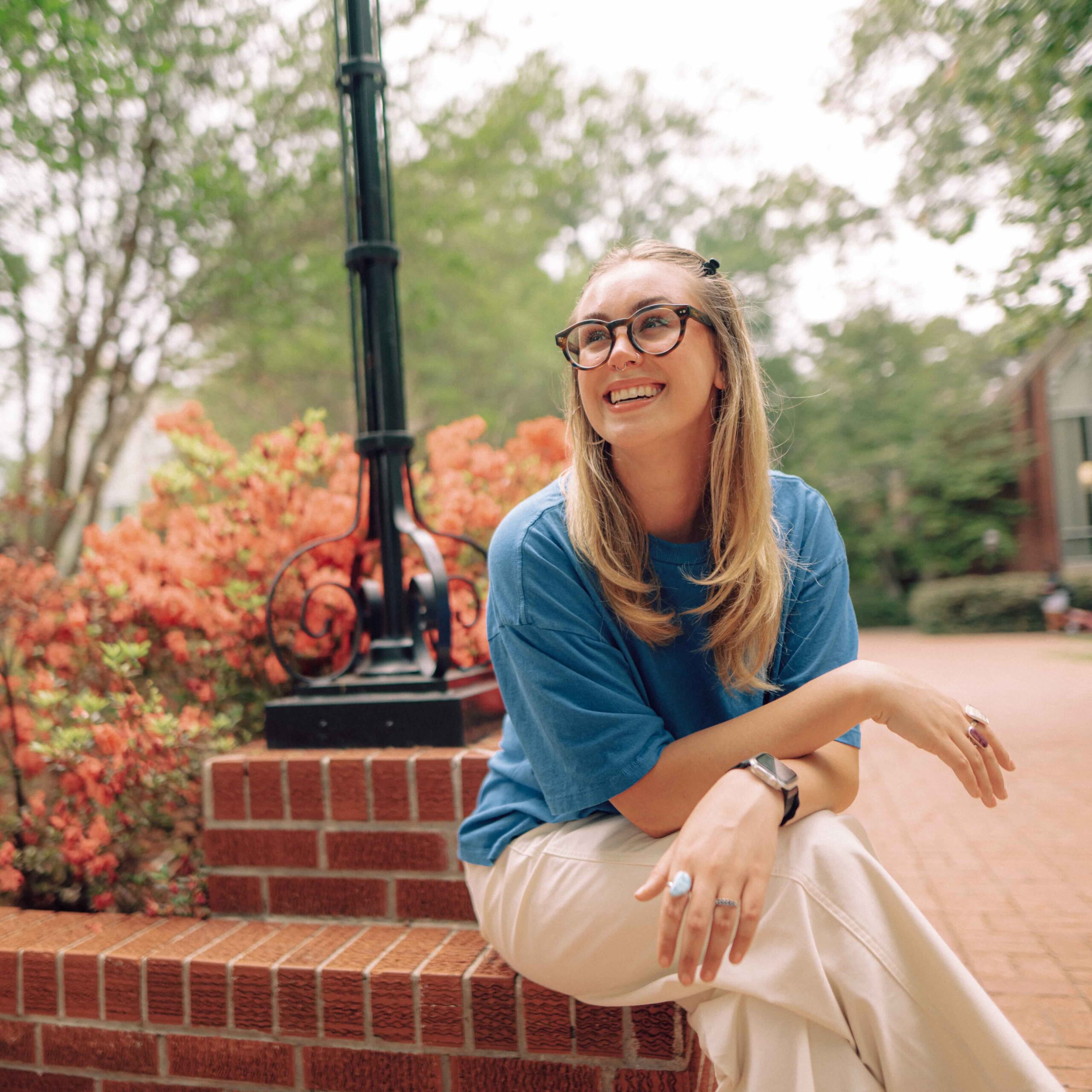 A smiling Hendrix student sitting on a brick wall.