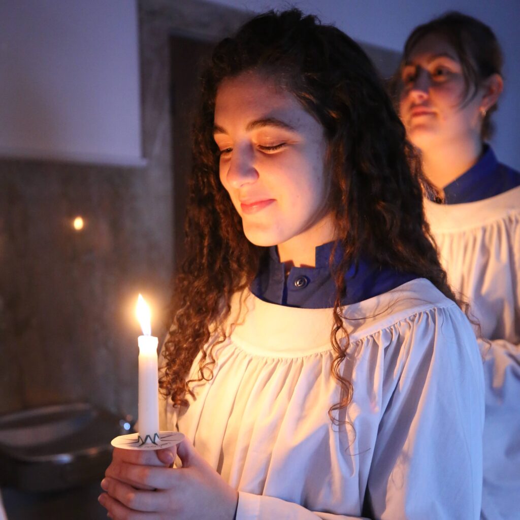 Students holding lit candles during a religious service.