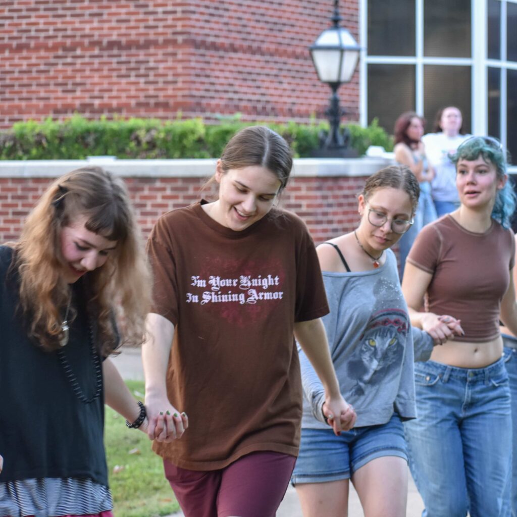 Students holding hands in a line while participating in an activity.