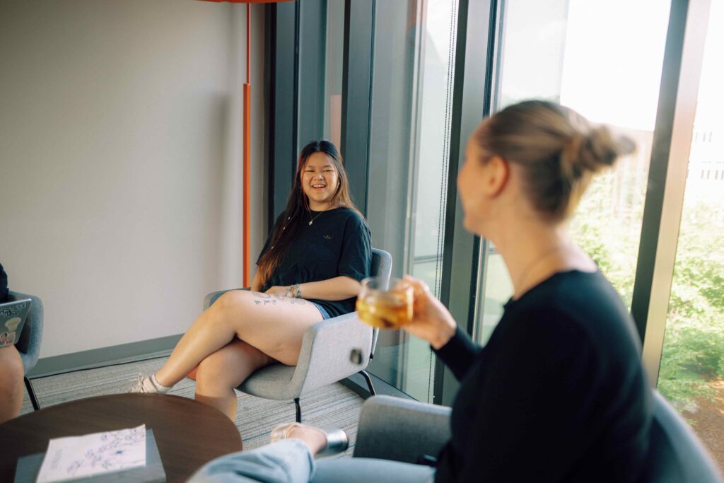 A small group of students laughing together while they sit in a lounge space on campus.