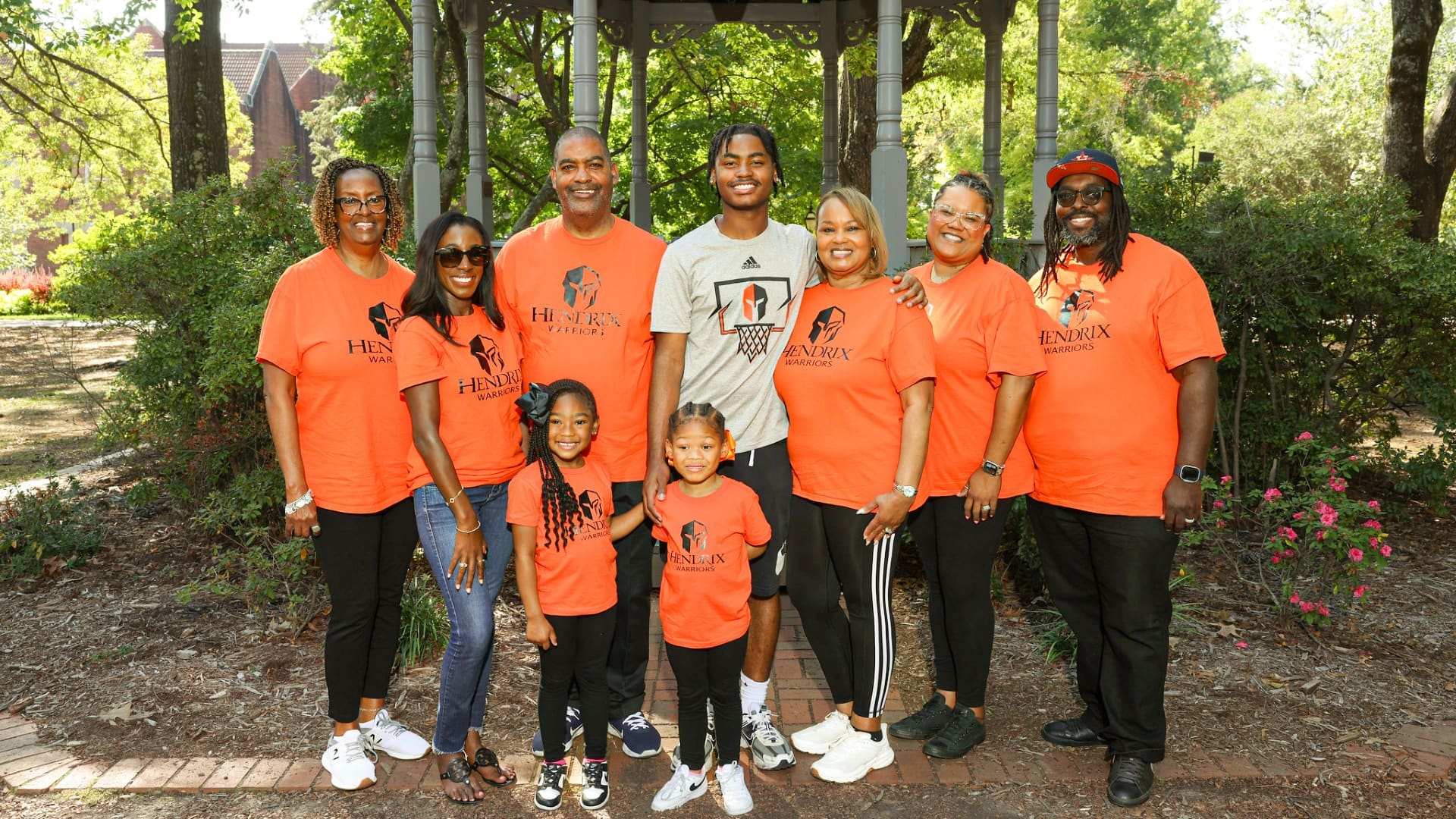 Nine people smiling while standing in front of the Hendrix gazebo on a sunny day.
