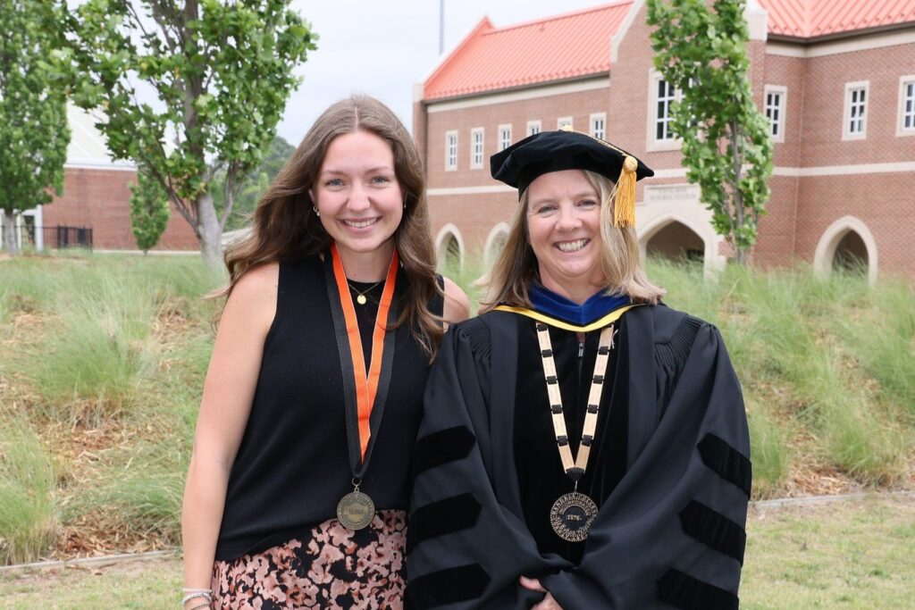 President Petersen stands in Commencement regalia alongside a President’s Medal recipient.