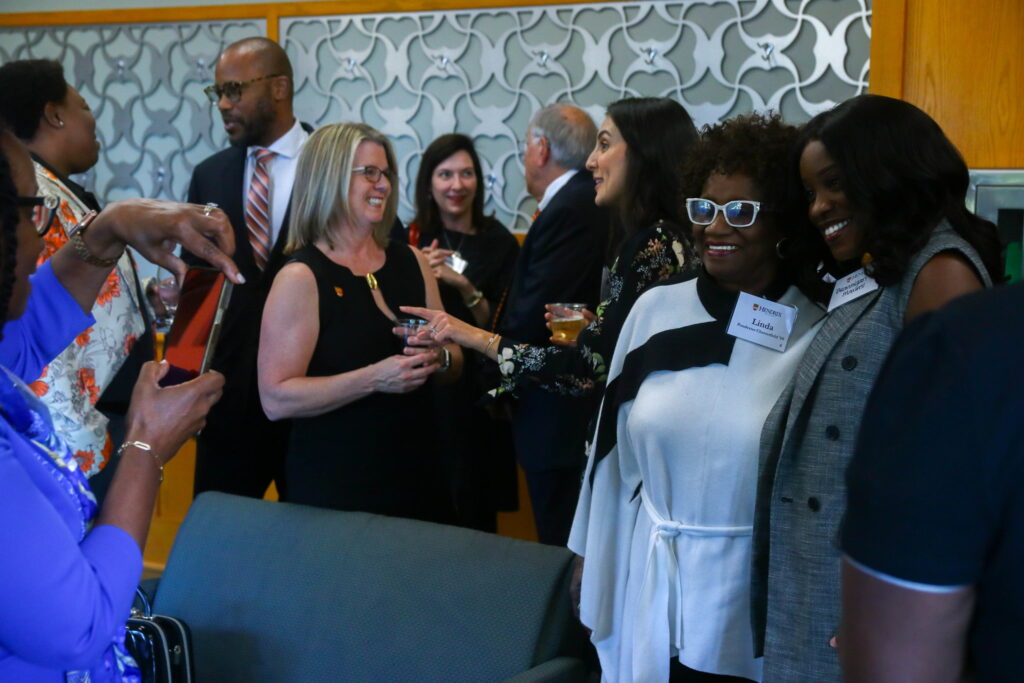 President Petersen speaks with a person at a crowded reception.