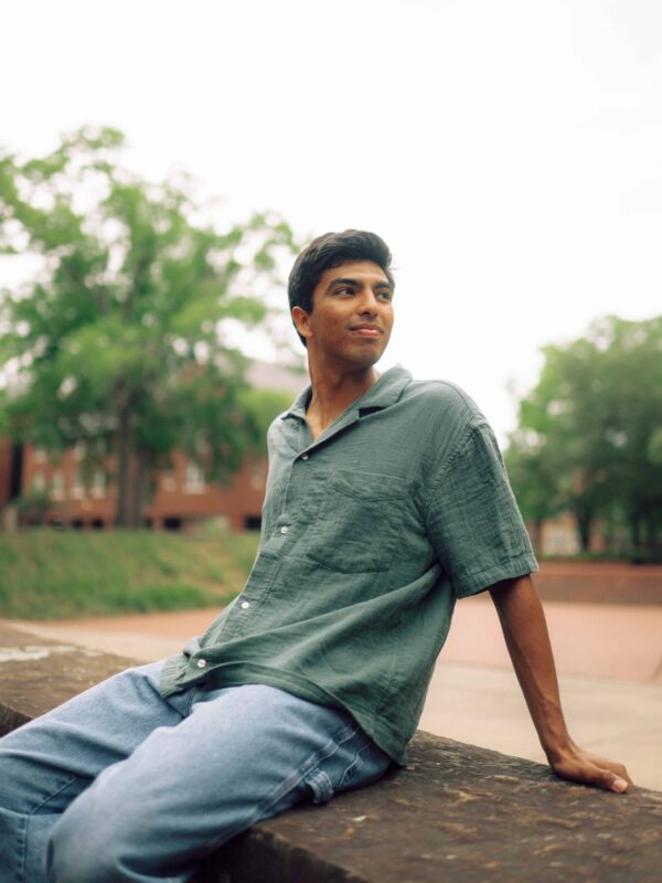 A student sitting on a stone wall on campus.
