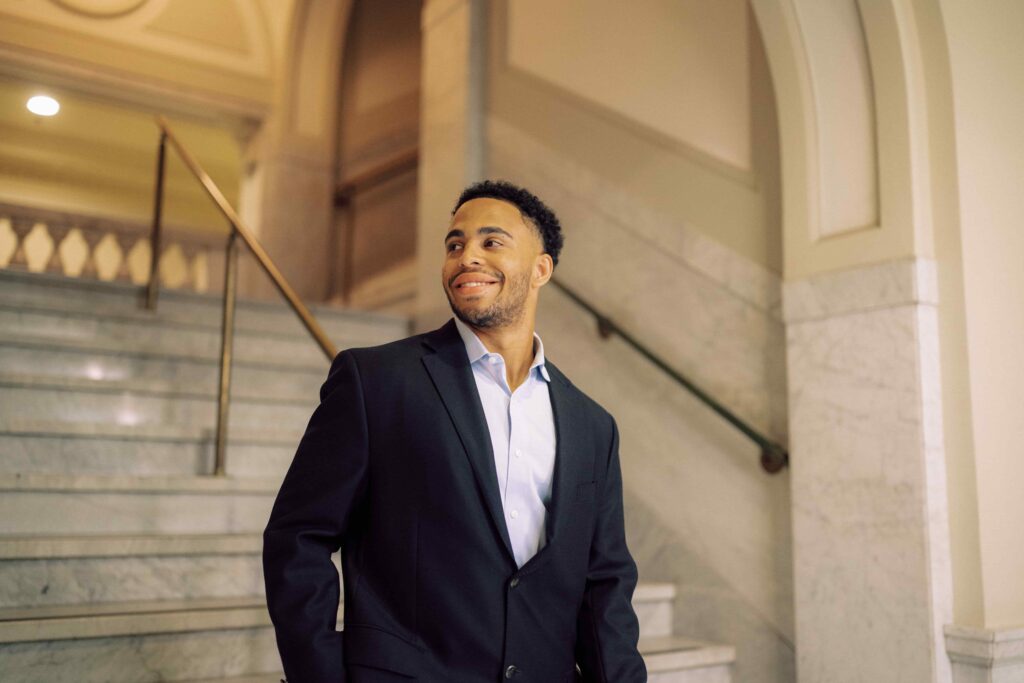 A man in a suit standing on marble steps inside a building.