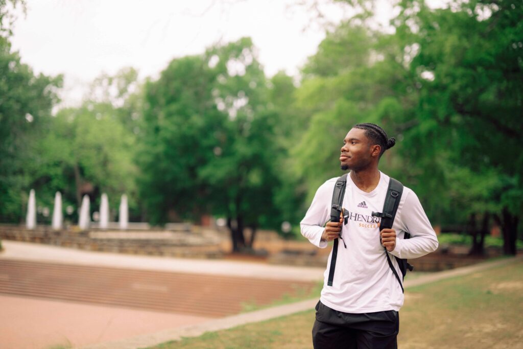 A student walking on campus with a backpack on.