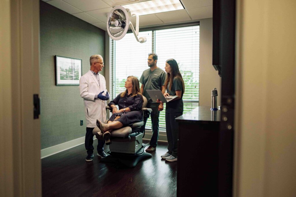 A doctor and two students speaking to a patient in an exam room.
