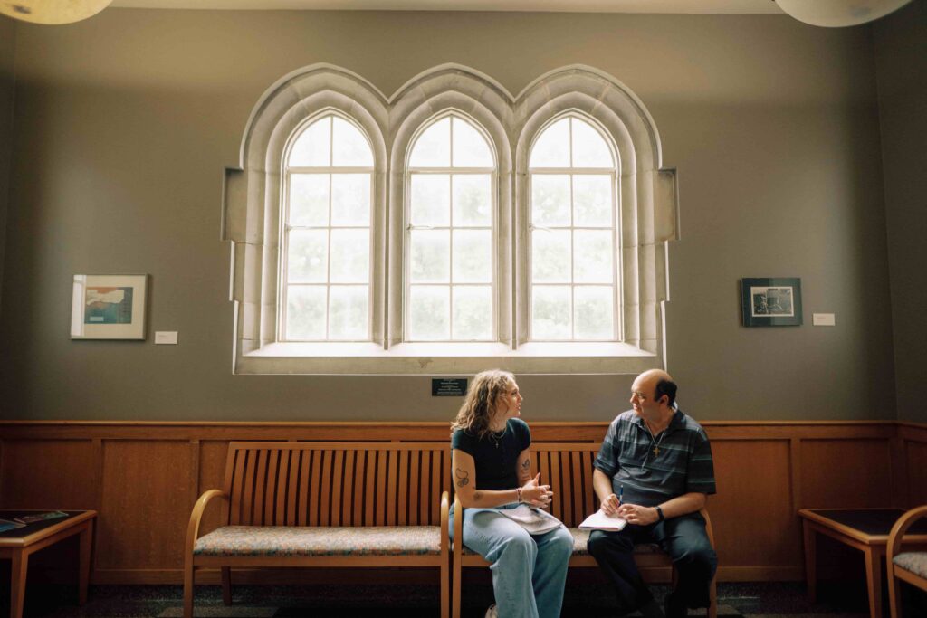 A student speaks with a faculty member in a building on campus.