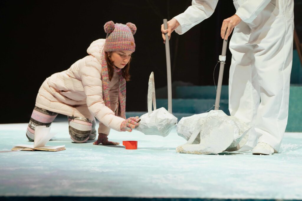 Two students performing on stage, with one of the students controlling a rabbit shaped puppet.
