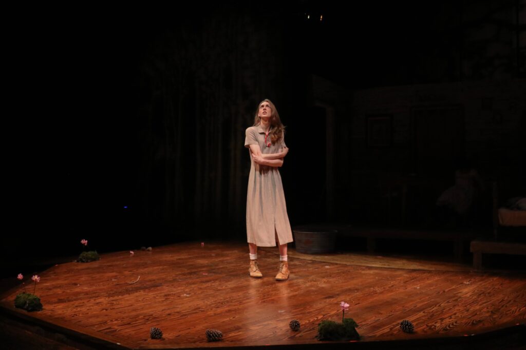 A woman in a long, plain dress performing on stage.