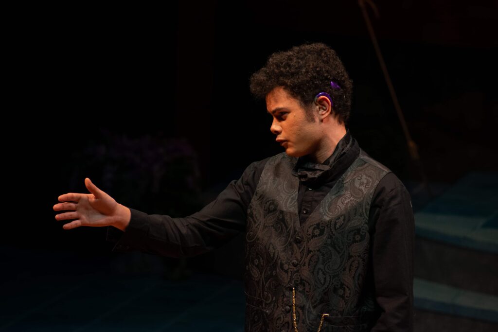 A student with his arm outstretched performing on stage.