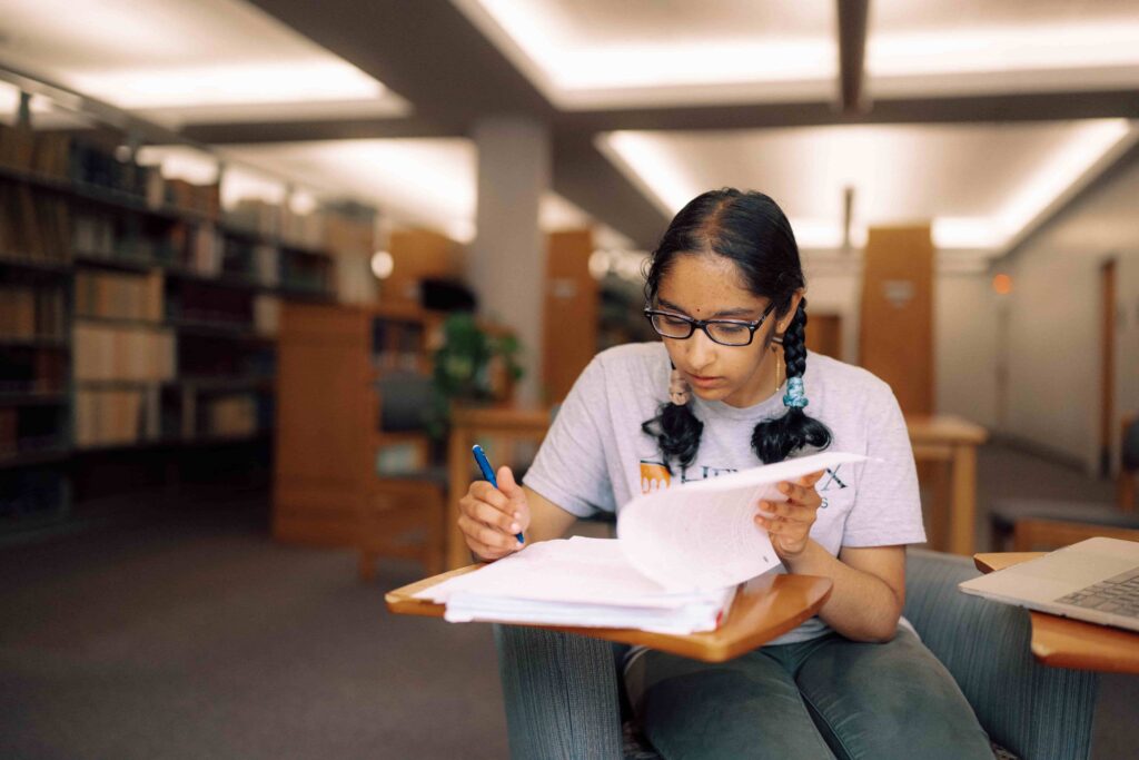 A student looking through her notes at a study desk in the library.