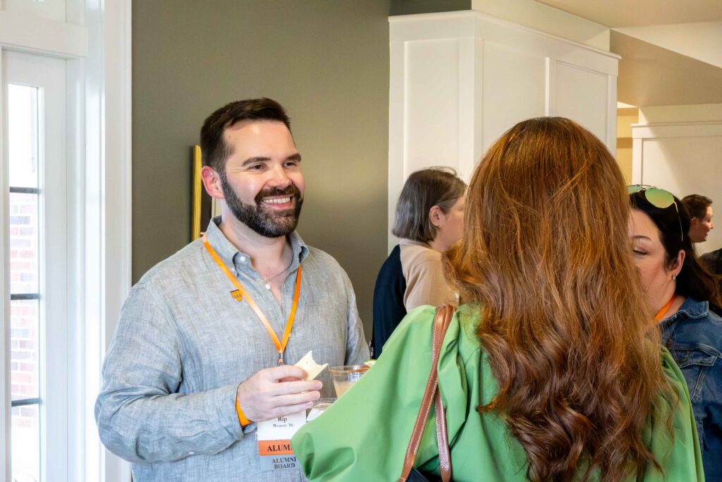 Two Hendrix alumni chatting with one another in a well-lit room.